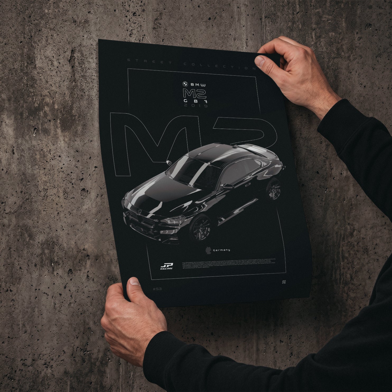 BMW M2 G87 2019 poster print held in hands against a concrete wall