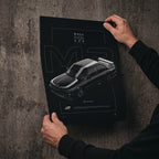 BMW M3 E30 1986 poster print held in hands against a concrete wall